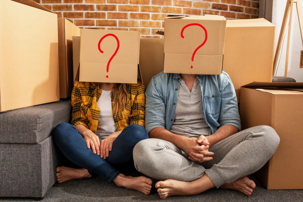 man and woman sitting in front of boxes with a question box as their head. 